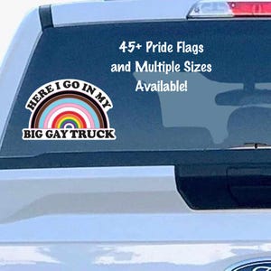 May include: A white sticker on a vehicle's window features a rainbow design with the text "HERE I GO IN MY BIG GAY TRUCK." Additional text reads "45+ Pride Flags and Multiple Sizes Available!" The sticker promotes LGBTQ+ pride.