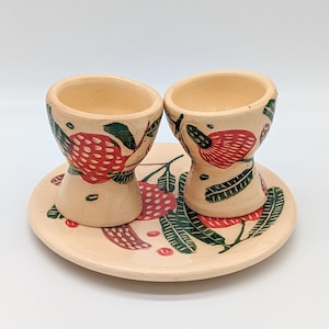 Peut inclure: Deux coquetiers en céramique avec un motif floral dans les tons rouge, vert et blanc, posés sur une assiette assortie.