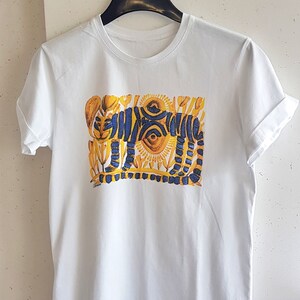 Op de afbeelding: Wit T-shirt met een blauwe en gele grafische print van een gestileerde tijger. De tijger is omringd door gele bloemen en zonnen.