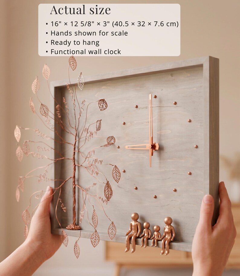 Puede incluir: Un reloj de pared rectangular de madera gris que mide 40,5 cm por 32 cm por 7,6 cm. Presenta un &aacute;rbol de alambre de color cobre con hojas recortadas a la izquierda y cuatro peque&ntilde;as figuras de cobre sentadas en el borde inferior del marco.