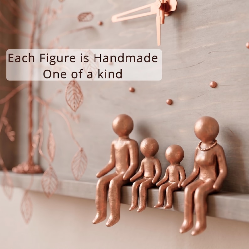 Puede incluir: Un reloj de pared de madera gris con un dise&ntilde;o de &aacute;rbol de alambre color cobre y cuatro figuras color cobre sentadas en una repisa. La esfera incluye manecillas de cobre y el texto: Each Figure is Handmade One of a kind.