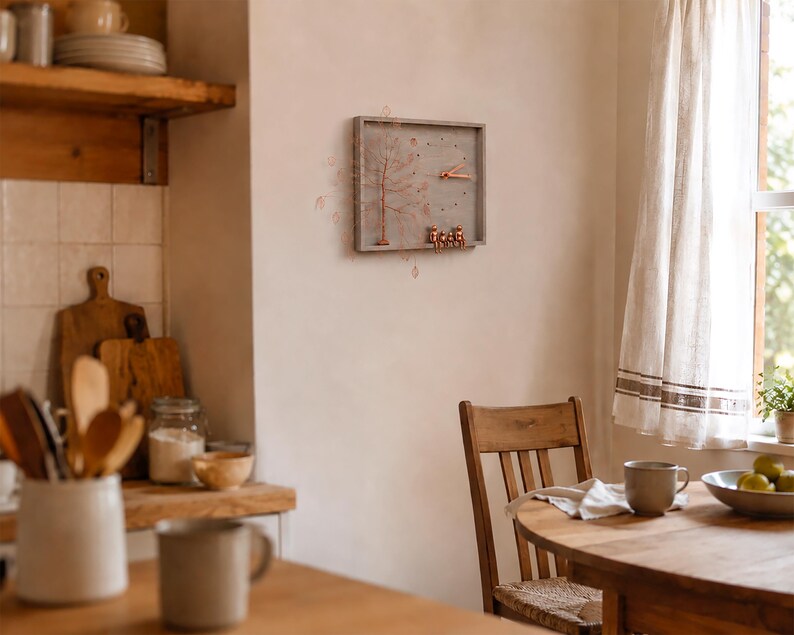 Puede incluir: Un reloj de pared rectangular con marco de madera gris, que presenta una escultura de &aacute;rbol de alambre color cobre en el lado izquierdo y tres peque&ntilde;as figuras color cobre sentadas en el borde inferior. Las manecillas son color cobre.