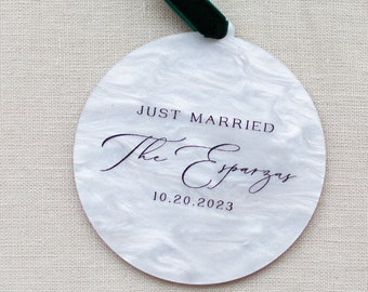 May include: A white round ornament with a green ribbon. The ornament says "Just Married" and "The Espargar" with the date "10.20.2023".