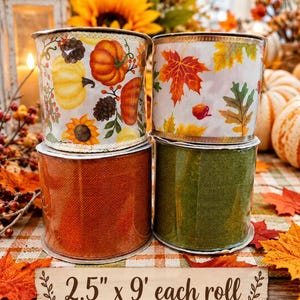 May include: Four rolls of ribbon stacked in two pairs. The top left roll features pumpkins, sunflowers, and pinecones. The top right roll displays autumn leaves. The bottom two rolls are solid orange and green textured fabric. Text reads 2.5" x 9' each roll.