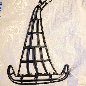 May include: Black metal witch hat decoration with a grid design. The hat has a curved brim and a pointed top, with a loop for hanging. The decoration is likely for Halloween or other seasonal displays.