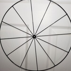 May include: A black metal wreath frame with 16 spokes. The frame is circular and has a diameter of approximately 12 inches.