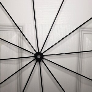 May include: A black metal wheel with spokes radiating out from a central hub. The wheel is against a white background.