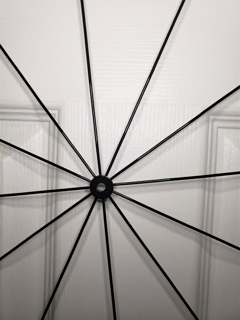 May include: A black metal wheel with spokes radiating out from a central hub. The wheel is against a white background.