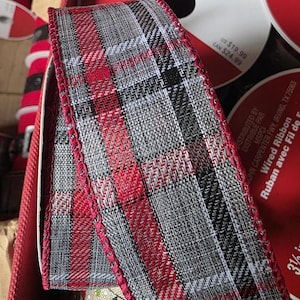 May include: Red and gray plaid wired ribbon with a silver metallic thread running through it. The ribbon has a scalloped edge.