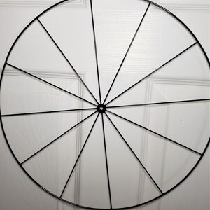 May include: A black metal wreath frame with 12 spokes radiating from the center.