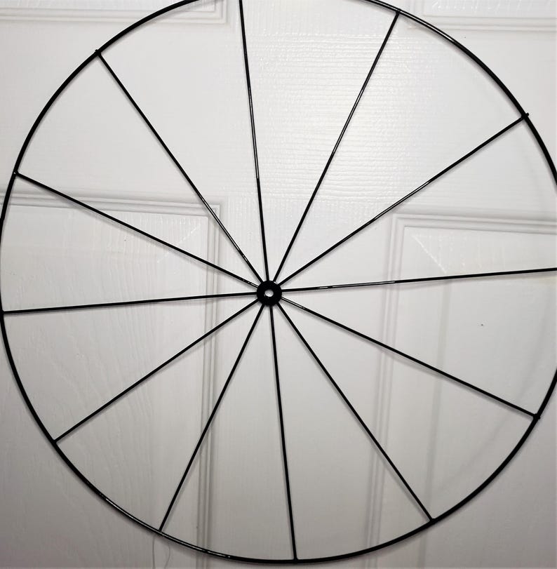 May include: A black metal wreath frame with 12 spokes radiating from the center.