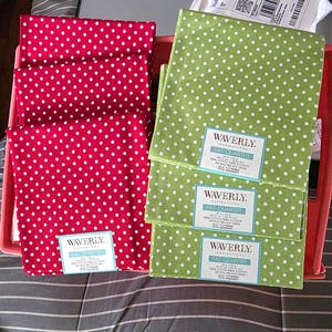 May include: Red and green fabric fat quarters with white polka dots. The fabric is labeled "Waverly Inspirations Fat Quarter". The red fabric is stacked in a pink container, and the green fabric is stacked next to it.