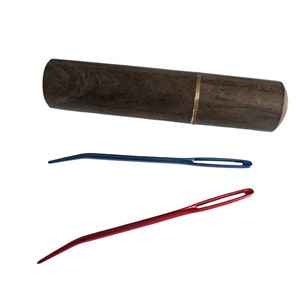 May include: A wooden case with a brass band containing two needles, one red and one blue.