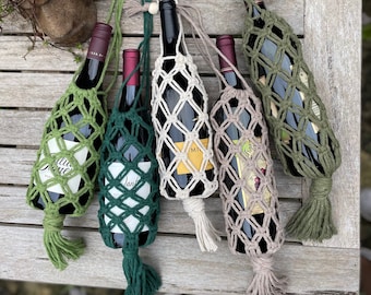 Puede incluir: Cinco porta botellas de vino hechos de macramé con borlas de diferentes colores. Los porta botellas están hechos de fibras naturales y tienen un aspecto rústico.