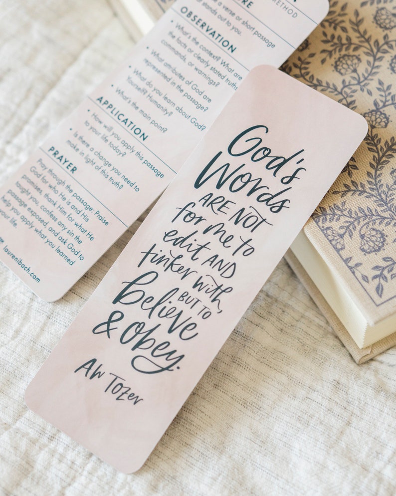 May include: A pink bookmark with a quote in black script that reads "God's Words Are Not For Me To Edit And Tinker With, But To Believe & Obey." The quote is attributed to A.W. Tozer.