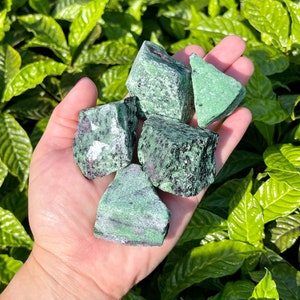 Peut inclure: Une collection de cinq pierres précieuses brutes de couleur verte et noire. Les pierres sont de forme irrégulière et ont un aspect marbré.