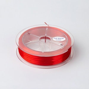 May include: A spool of bright red thread wound around a clear plastic bobbin. The bobbin has a label that reads "#6001".