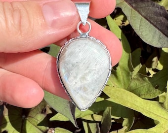 May include: A teardrop-shaped pendant with a white moonstone set in a silver frame.