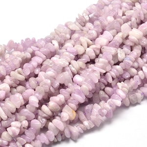 May include: A strand of pale pink and white gemstone beads, with a slightly irregular, chip-like shape. The beads are strung on a thin, clear thread.