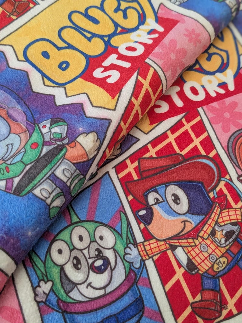 May include: A colorful fabric featuring comic book style panels with cartoon characters. The panels include the text "BLUE STORY" and images of a space ranger, a three-eyed alien, and a dog dressed as a cowboy.