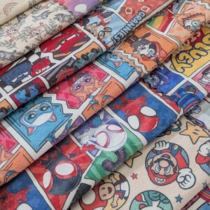 May include: A stack of colorful fabric featuring comic book panels and cartoon characters. Designs include Spider-Man, Mario, Lightning McQueen, and other popular characters. The fabric has a soft, plush texture and a variety of bright colors.