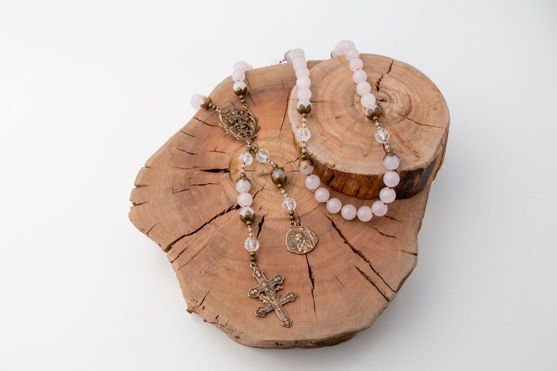 The Saint Joan of Arc rosary is draped over the large and small tree rings which are stacked on each other