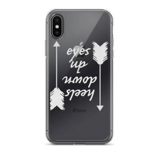 Pode incluir: Uma capa transparente para telefone com um design branco de flechas e o texto "Keep your eyes up".