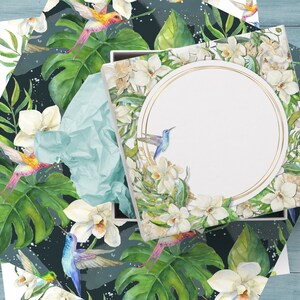 May include: A white gift box with a gold circle frame and a watercolor design of white orchids, green leaves, and blue and orange hummingbirds. The box is open and the inside is white.