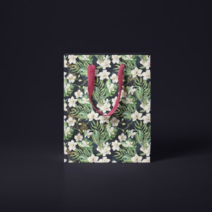 May include: A white gift bag with a floral pattern featuring white orchids and green leaves. The bag has red handles.