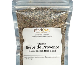 May include: A silver resealable pouch filled with dried herbs labeled "Organic Herbs de Provence Classic French Herb Blend". The label also includes the text "pinch spice market Louisville, KY 40206 www.pinchspicemarket.com" and "Handcrafted in Louisville".