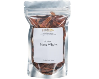 May include: A silver resealable pouch filled with organic whole mace, a spice with a reddish-brown color. The pouch has a label that reads "Pinch Spice Market, Louisville, KY 40203, www.pinchspicemarket.com, Organic Mace Whole, Product of Sri Lanka."