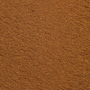 May include: A finely ground, dry spice powder with a uniform, rich medium-brown color. The texture appears granular and consistent across the entire surface, showing small, scattered particles and a matte finish throughout the composition.