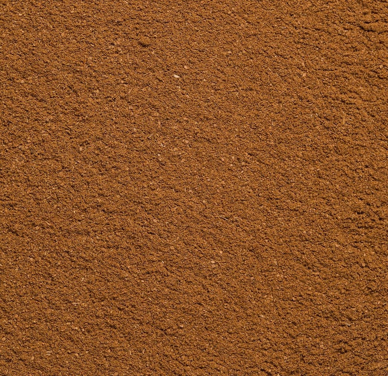May include: A finely ground, dry spice powder with a uniform, rich medium-brown color. The texture appears granular and consistent across the entire surface, showing small, scattered particles and a matte finish throughout the composition.