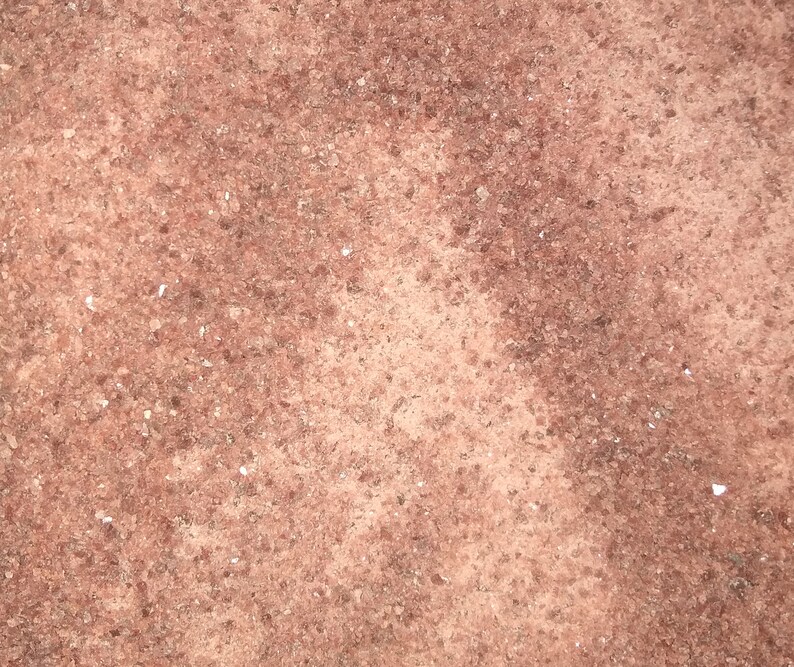 May include: Close-up of a reddish-brown textured surface with a grainy appearance. The surface has a slightly uneven texture with a subtle variation in color.