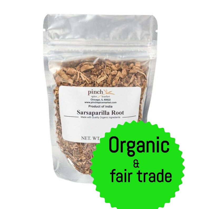 May include: A clear plastic bag filled with dried brown sarsaparilla root. The bag has a label that reads "pinch spice market" and "Sarsaparilla Root". The label also states that the product is organic and fair trade.