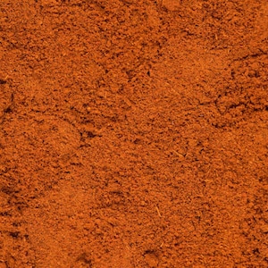 May include: Close-up of a pile of ground cinnamon, a warm brown spice with a slightly reddish hue.