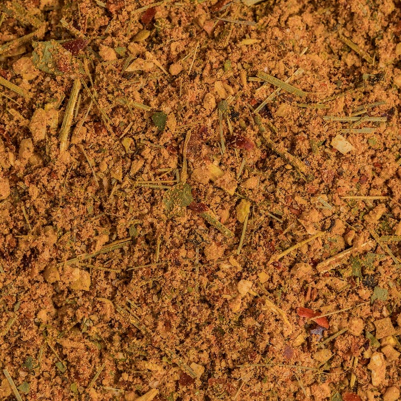 May include: A close-up of a blend of dried herbs and spices, including red pepper flakes, dried herbs, and other spices.