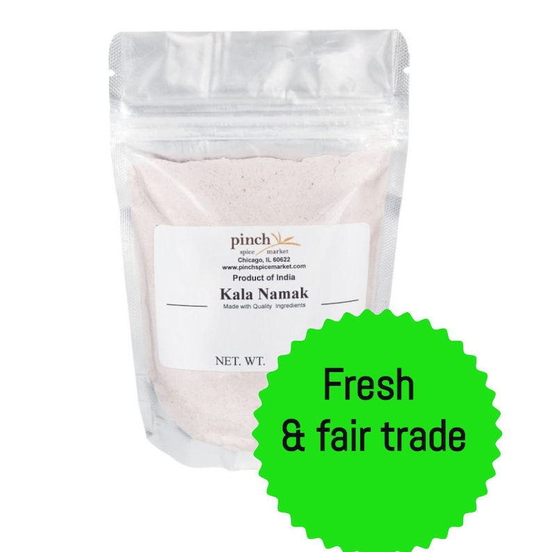 May include: A white resealable pouch filled with pink Himalayan salt labeled "Kala Namak" with the text "pinch spice market" and "Product of India". A green sticker with the text "Fresh & fair trade" is on the front of the pouch.