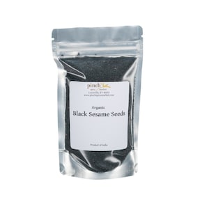 May include: A silver resealable pouch filled with black sesame seeds. The pouch has a white label with the text "Pinch Spice Market, Louisville, KY 40203, www.pinchspicemarket.com, Organic Black Sesame Seeds, Product of India."