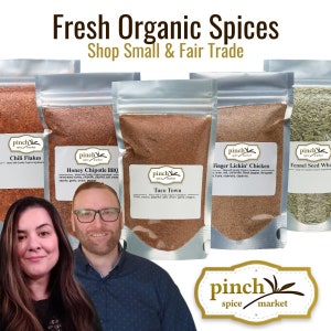 May include: Five clear plastic pouches with different organic spice blends. The pouches are labeled with the brand name "pinch spice market" and the names of the spices: "Chili Flakes", "Honey Chipotle BBQ", "Taco Town", "Finger Lickin' Chicken", and "Fennel Seed Whole". The pouches are arranged in a row on a white background.