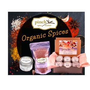 Pode incluir: Um conjunto de especiarias org&acirc;nicas numa caixa castanha com um r&oacute;tulo rosa e branco que diz "pinch spice market". A caixa cont&eacute;m seis pequenos frascos de especiarias, incluindo sal de trufa negra, sal de cogumelo porcini e especiarias para grelhar. A caixa &eacute; rodeada por v&aacute;rias especiarias, incluindo flocos de pimenta vermelha, sementes de s&eacute;samo e anis estrelado.