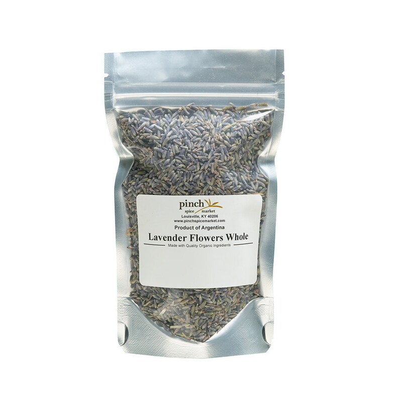 May include: A clear, sealed bag filled with dried lavender flowers. The bag has a white label with the text "Lavender Flowers Whole" and "Product of Argentina". The lavender is a mix of purple and gray.