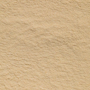 May include: Close-up of a light beige powder, showing its fine texture and smooth surface.
