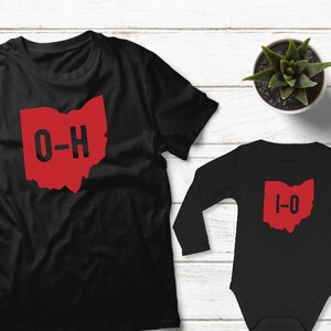 May include: A black t-shirt with a red outline of the state of Ohio and the text "O-H" inside. A black long-sleeved babygrow with a red outline of the state of Ohio and the text "I-O" inside.