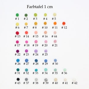 Op de afbeelding: Kleurenkaart met 42 viltballen, elk 1 cm in diameter, gerangschikt in rijen en genummerd. De kleuren omvatten groen, geel, oranje, rood, roze, paars, blauw, turquoise, grijs en zwart.