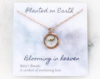 May include: A gold necklace with a round pendant containing a preserved baby's breath flower. The card reads "Planted on Earth, Blooming in Heaven. Baby's Breath: A symbol of everlasting love."