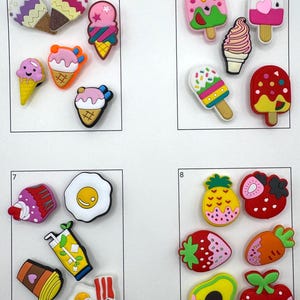 May include: A collection of colorful, decorative charms featuring ice cream cones, popsicles, and various food items. The charms are in vibrant colors like pink, yellow, and red, with detailed designs. The collection includes a fried egg, coffee cup, and fruit.