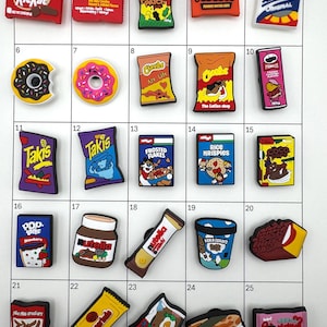 May include: A collection of colorful food-themed charms, including Kit Kat, Skittles, Sour Patch, Reese's, and more. The charms feature various snack brands and treats, perfect for adding to shoes or accessories.