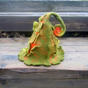 Puede incluir: Un gorro de gnomo de fieltro verde y naranja con un borde rizado. El gorro está hecho de lana fieltro y tiene una superficie texturizada.