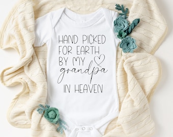 May include: White baby onesie with black text that reads "Hand picked for earth by my grandpa in heaven" with a heart symbol.